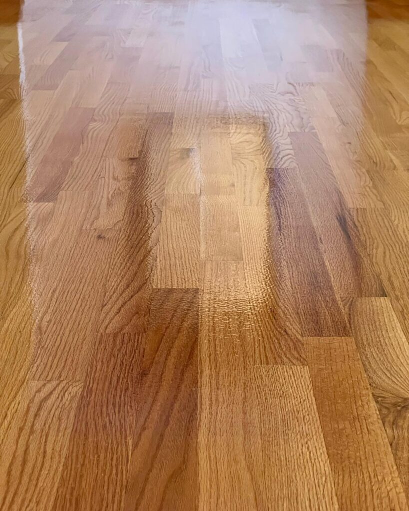 Close-up of the rich, detailed texture of a hardwood floor in Philadelphia, showing the seamless finish achieved in the ninth refinishing project. The varying shades of the wood planks create a harmonious pattern, reflecting the ambient light.